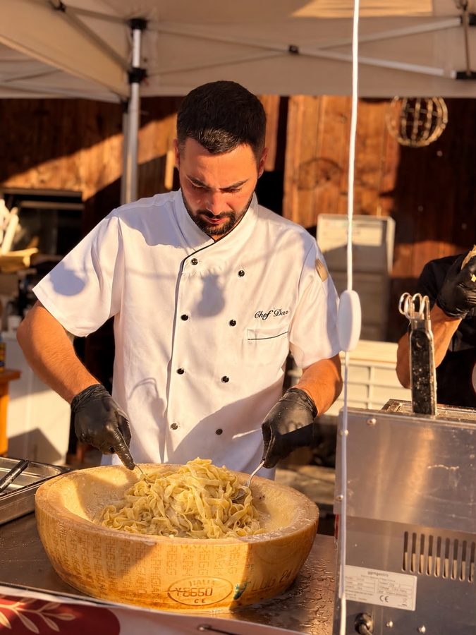 Der Koch schwenkt Pasta im ausgehöhlten Käserad.